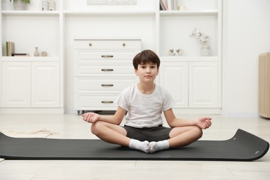 Photo of Boy doing exercise on fitness mat at home. Sport activity