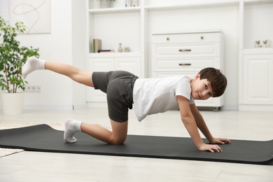 Photo of Boy doing exercise on fitness mat at home. Sport activity