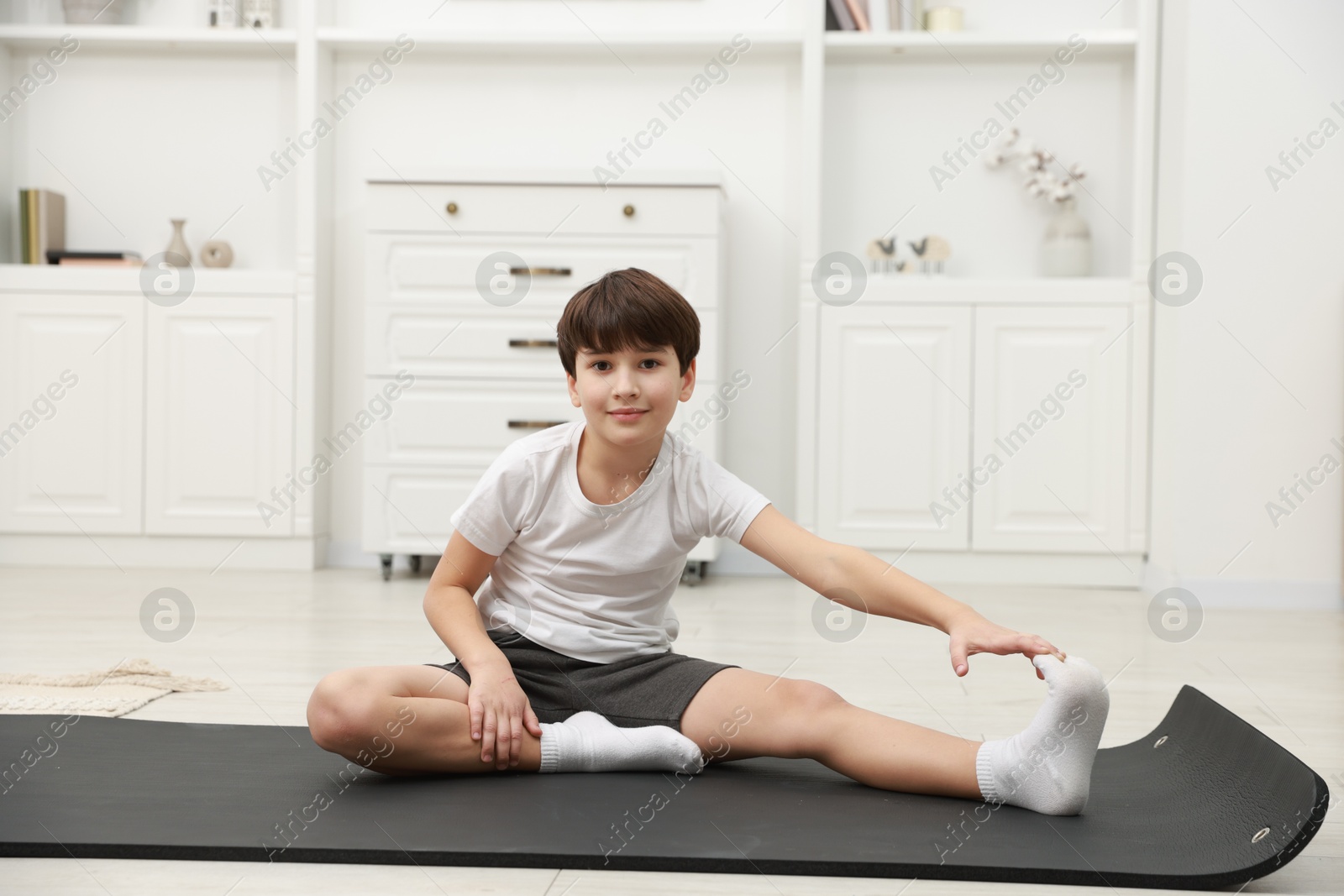 Photo of Boy doing exercise on fitness mat at home. Sport activity