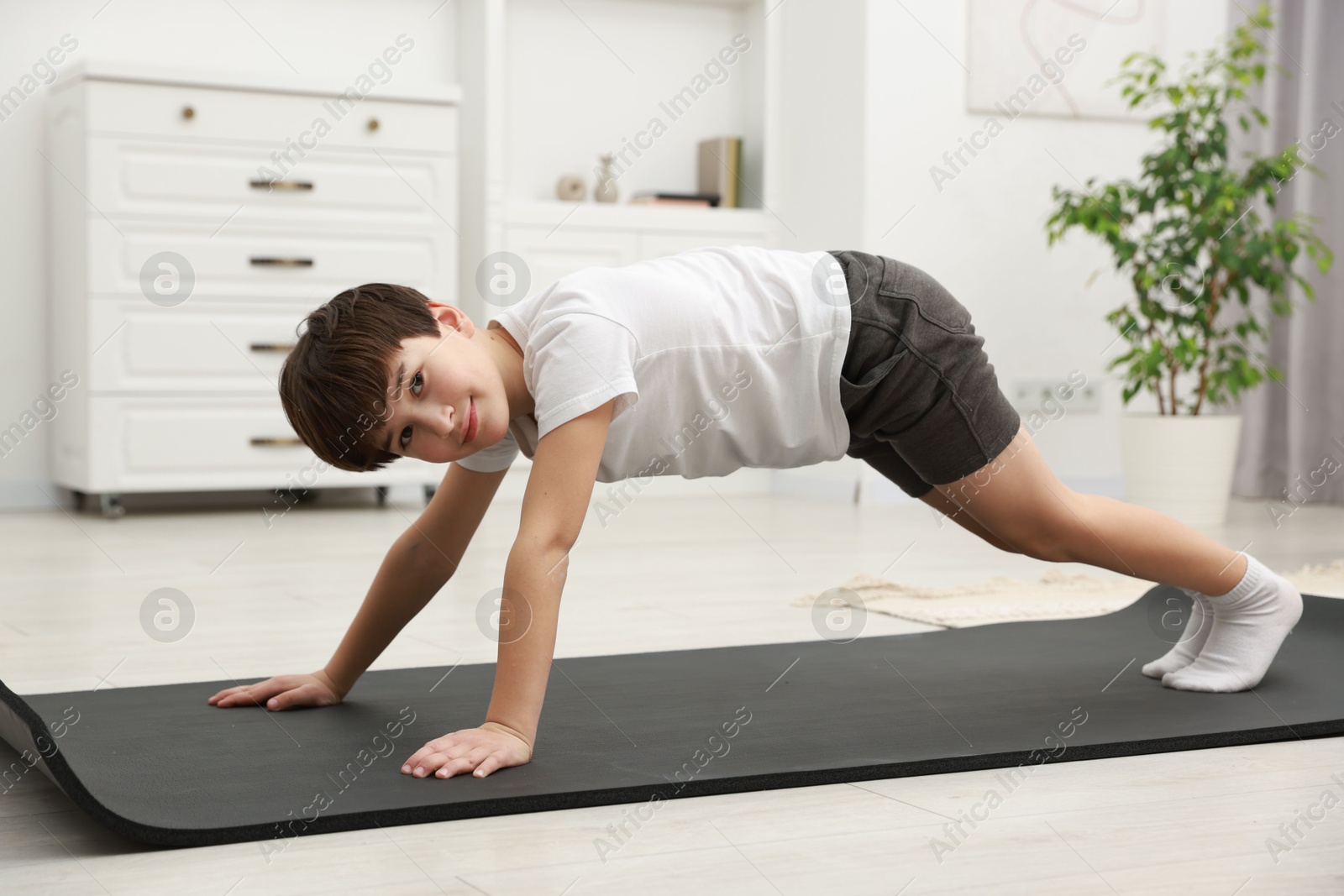 Photo of Boy doing exercise on fitness mat at home. Sport activity