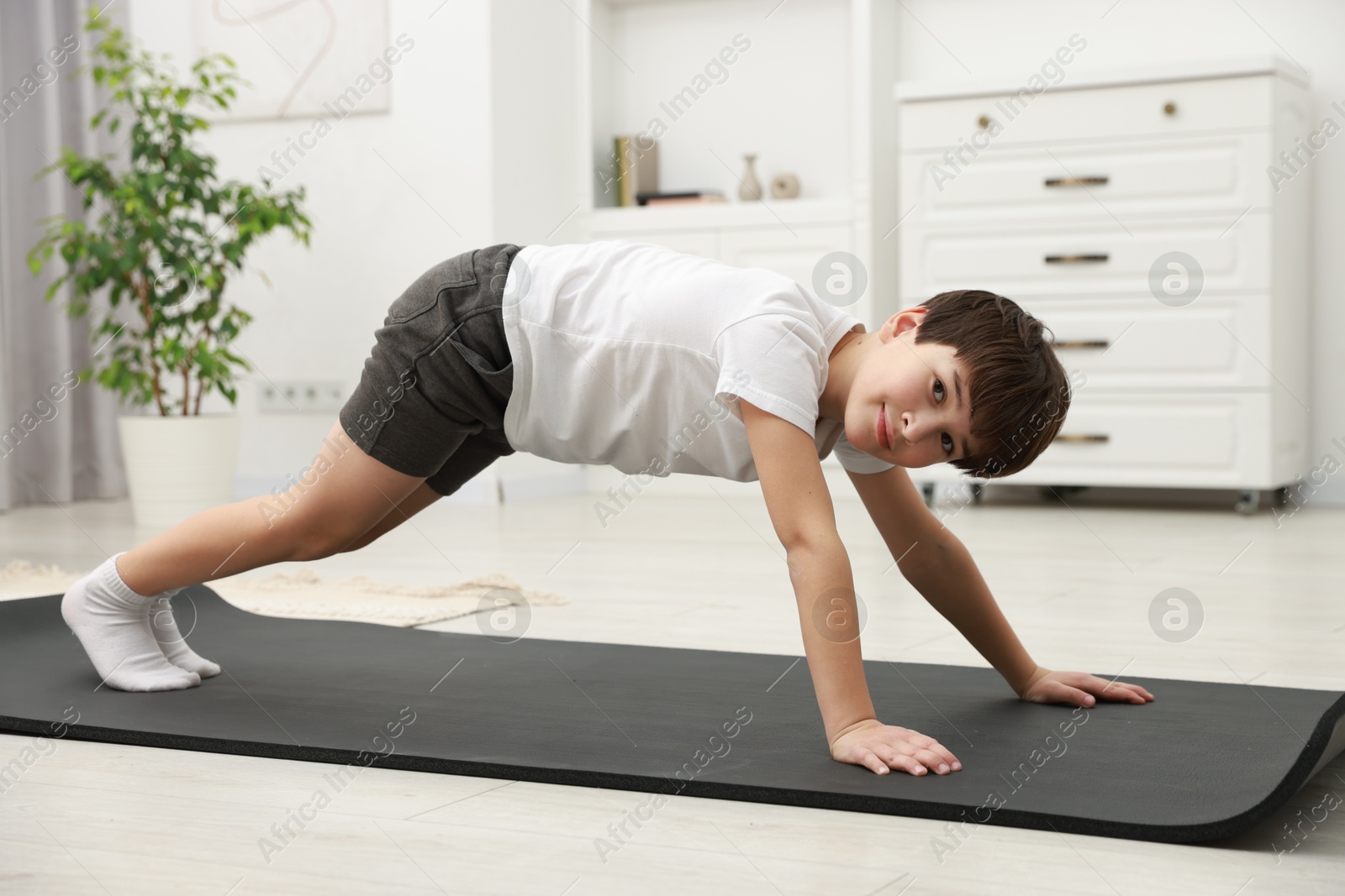 Photo of Boy doing exercise on fitness mat at home. Sport activity