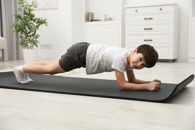 Photo of Boy doing exercise on fitness mat at home. Sport activity