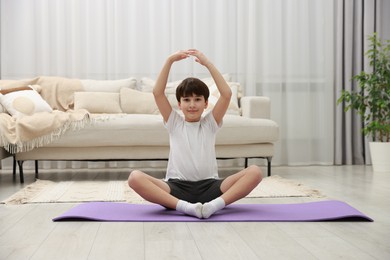 Photo of Boy doing exercise on fitness mat at home. Sport activity