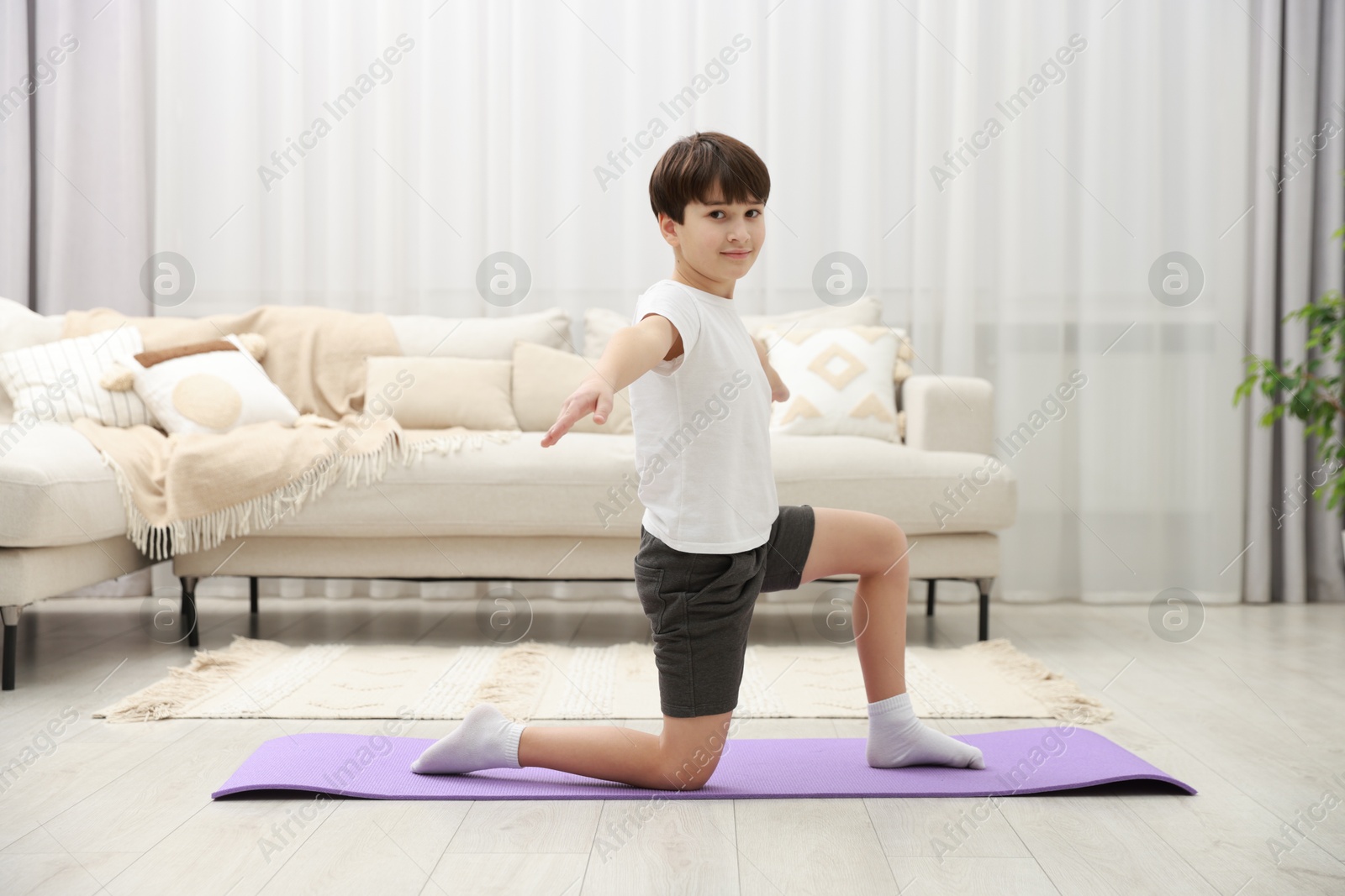 Photo of Boy doing exercise on fitness mat at home. Sport activity