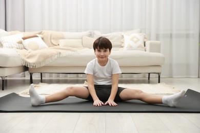 Photo of Boy doing exercise on fitness mat at home. Sport activity