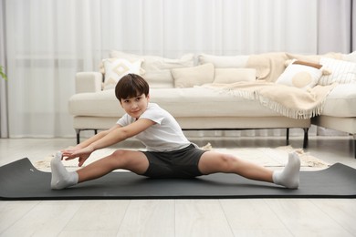 Photo of Boy doing exercise on fitness mat at home. Sport activity