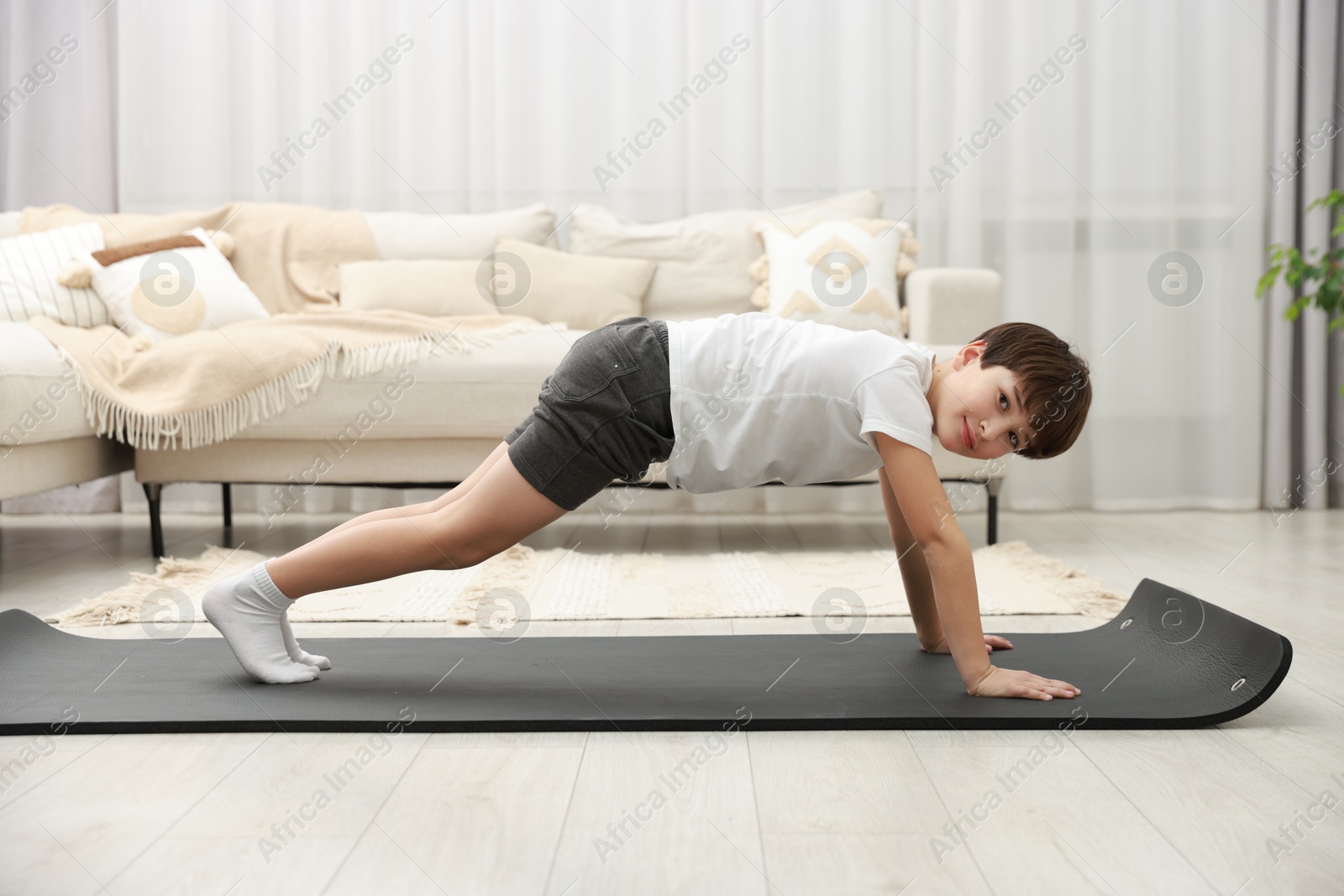 Photo of Boy doing exercise on fitness mat at home. Sport activity