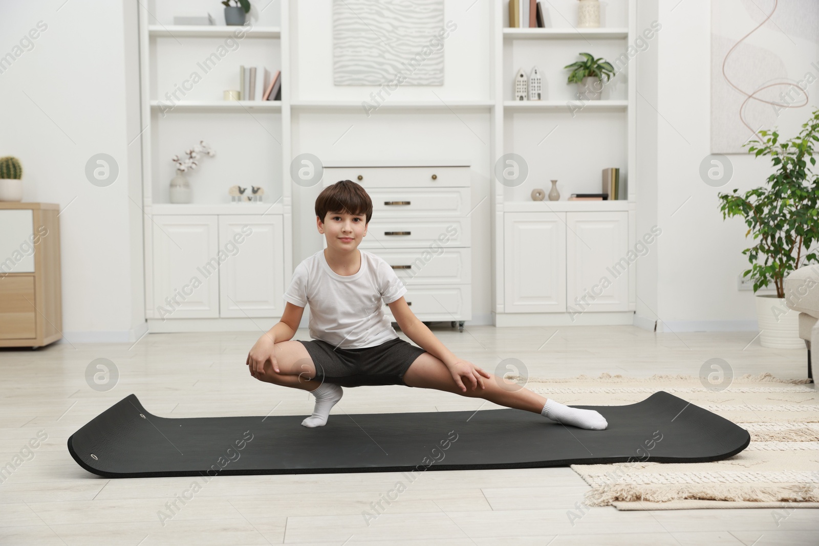 Photo of Boy doing exercise on fitness mat at home. Sport activity