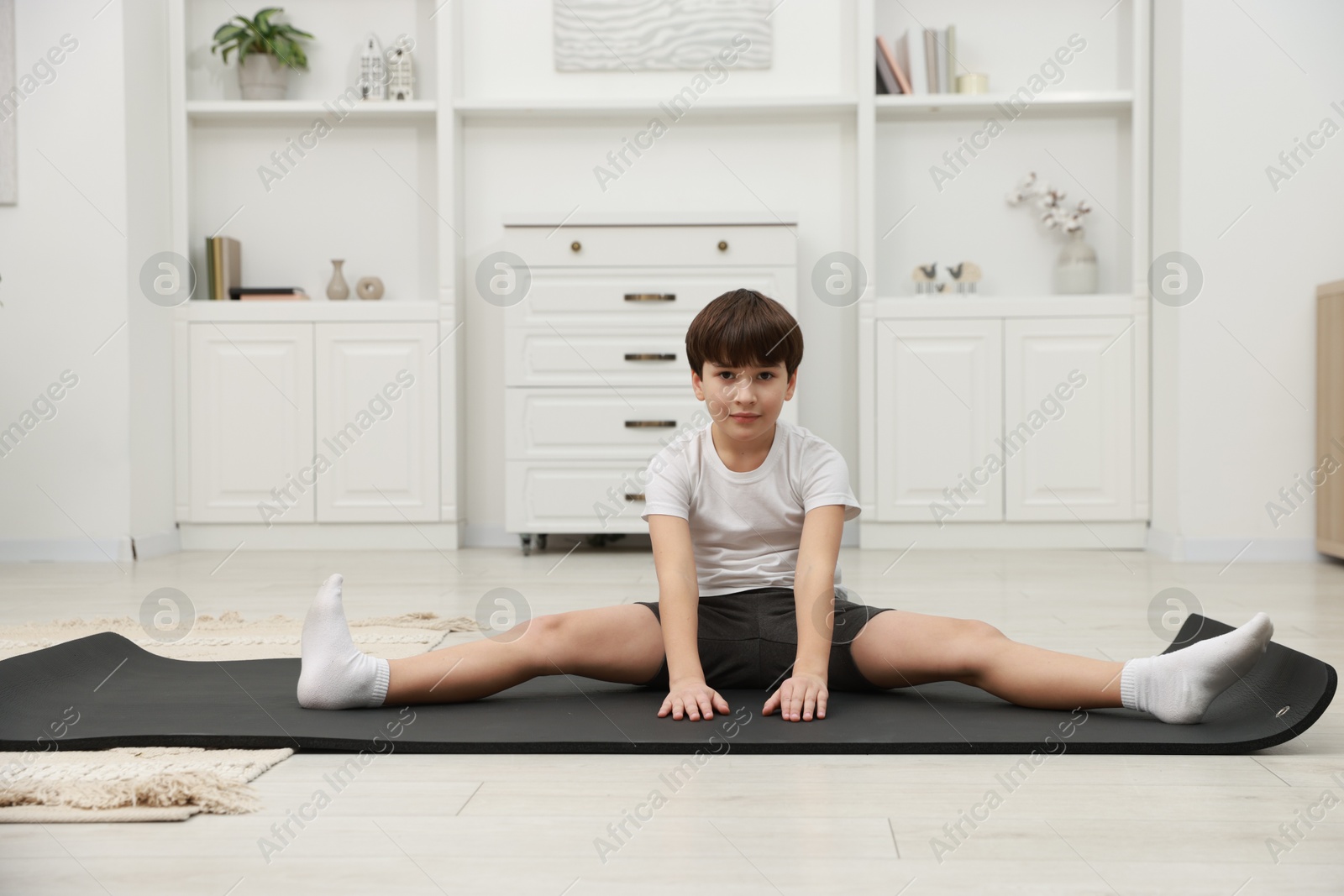 Photo of Boy doing exercise on fitness mat at home. Sport activity