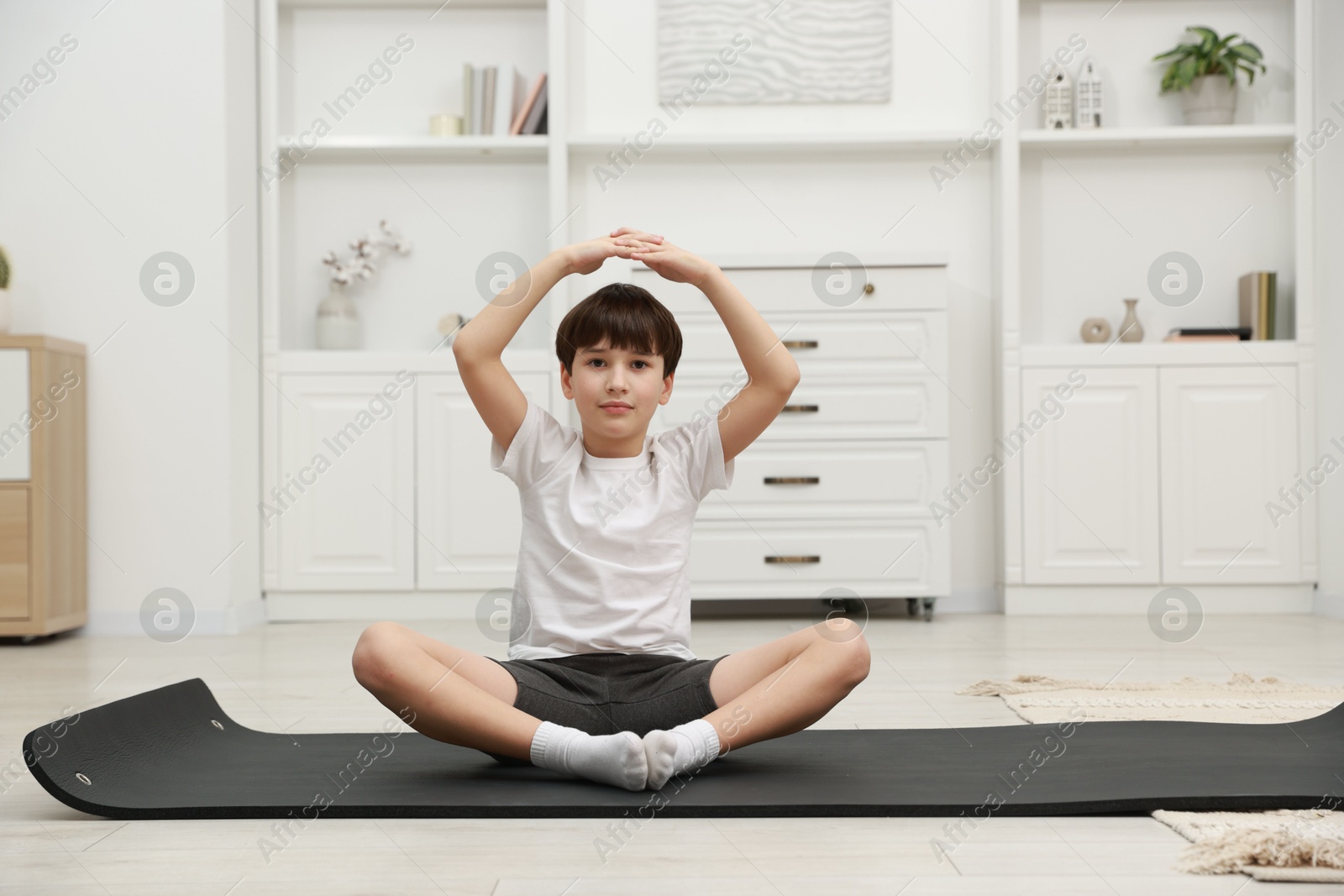 Photo of Boy doing exercise on fitness mat at home. Sport activity