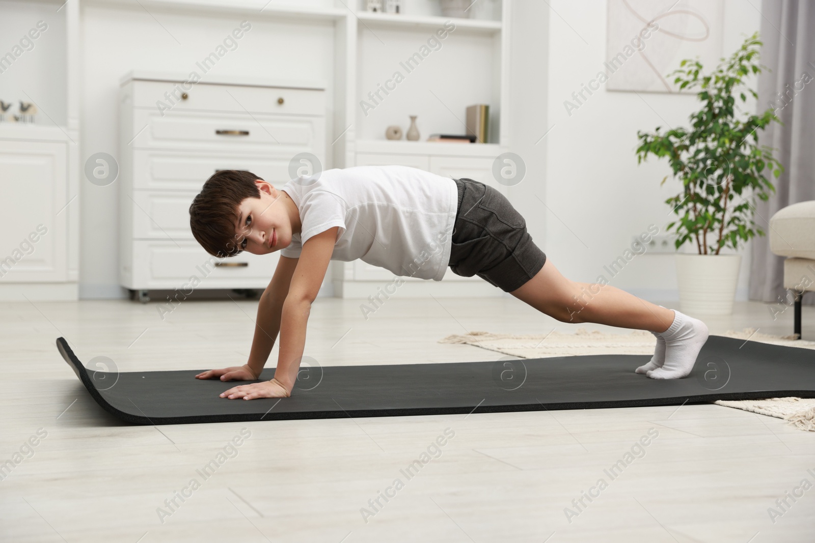 Photo of Boy doing exercise on fitness mat at home. Sport activity