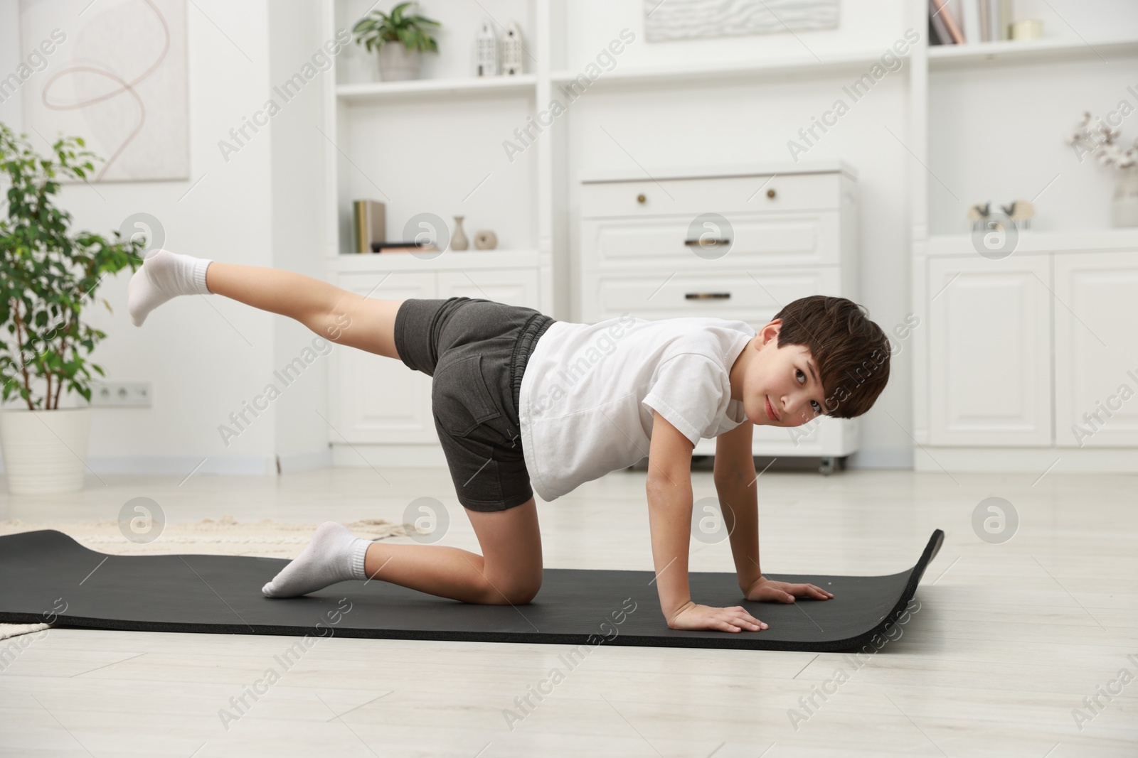 Photo of Boy doing exercise on fitness mat at home. Sport activity