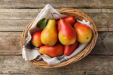 Photo of Ripe juicy pears in wicker basket on wooden table, top view