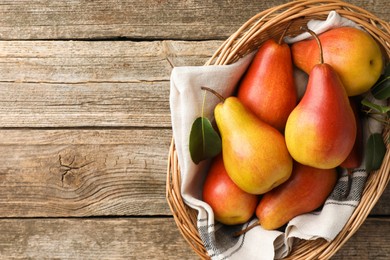 Photo of Ripe juicy pears in wicker basket on wooden table, top view. Space for text