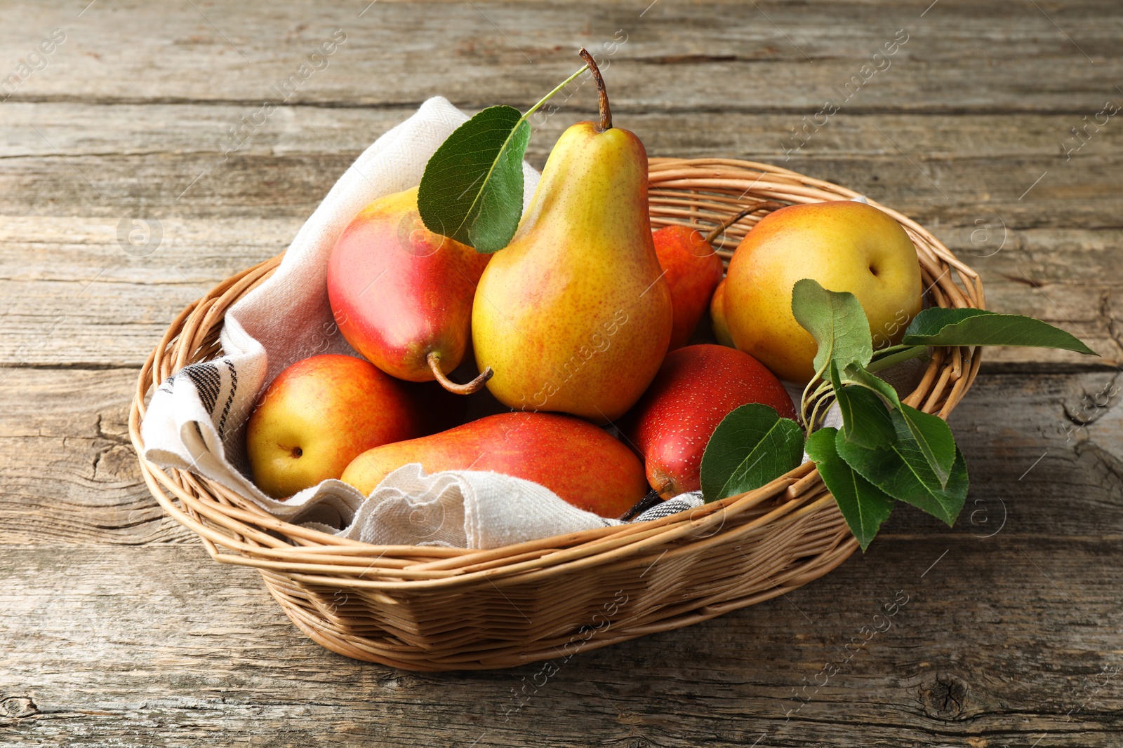 Photo of Ripe juicy pears in wicker basket on wooden table