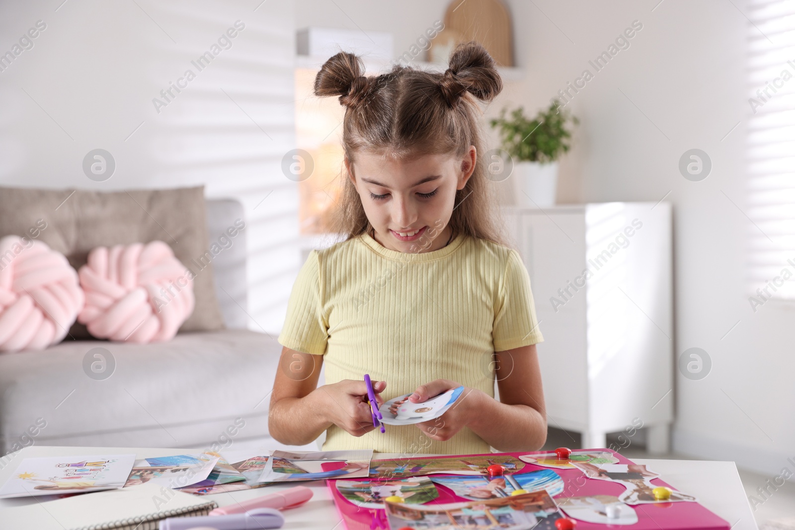 Photo of Creating vision board. Girl cutting out picture at light table indoors