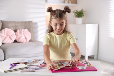 Photo of Girl creating vision board with different pictures at light table indoors