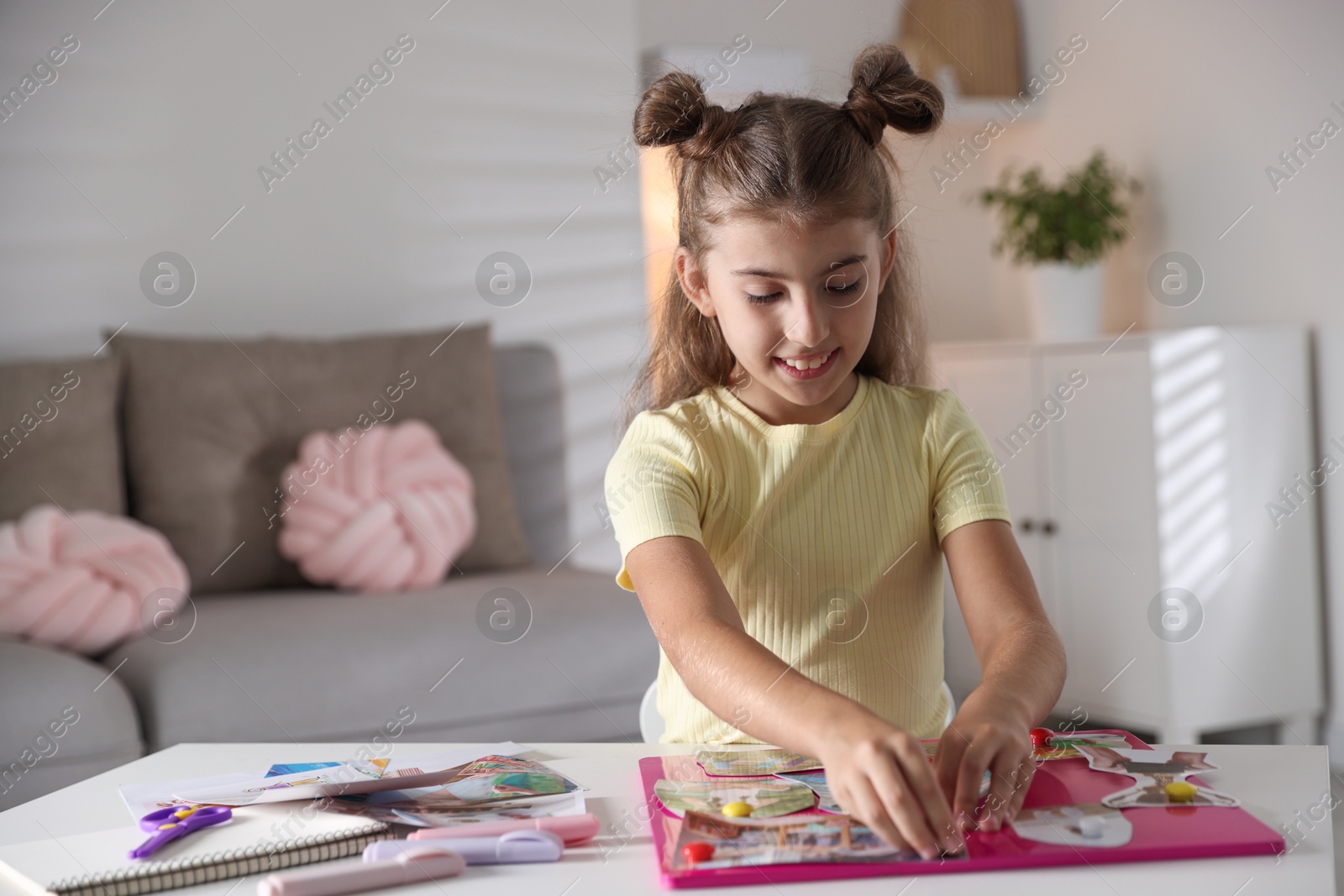 Photo of Girl creating vision board with different pictures at light table indoors