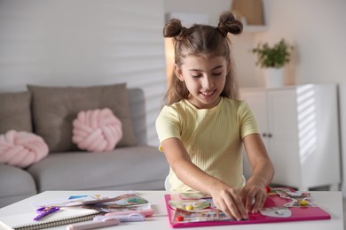 Girl creating vision board with different pictures at light table indoors