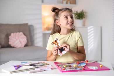 Creating vision board. Girl with picture of golden cup trophy at light table indoors