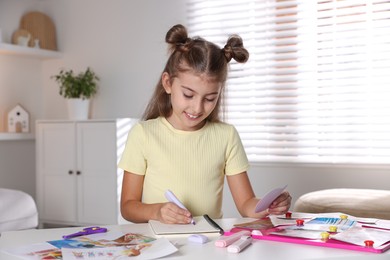 Creating vision board. Girl drawing something with violet marker at light table indoors