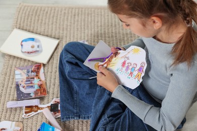 Creating vision board. Girl cutting out picture on floor indoors