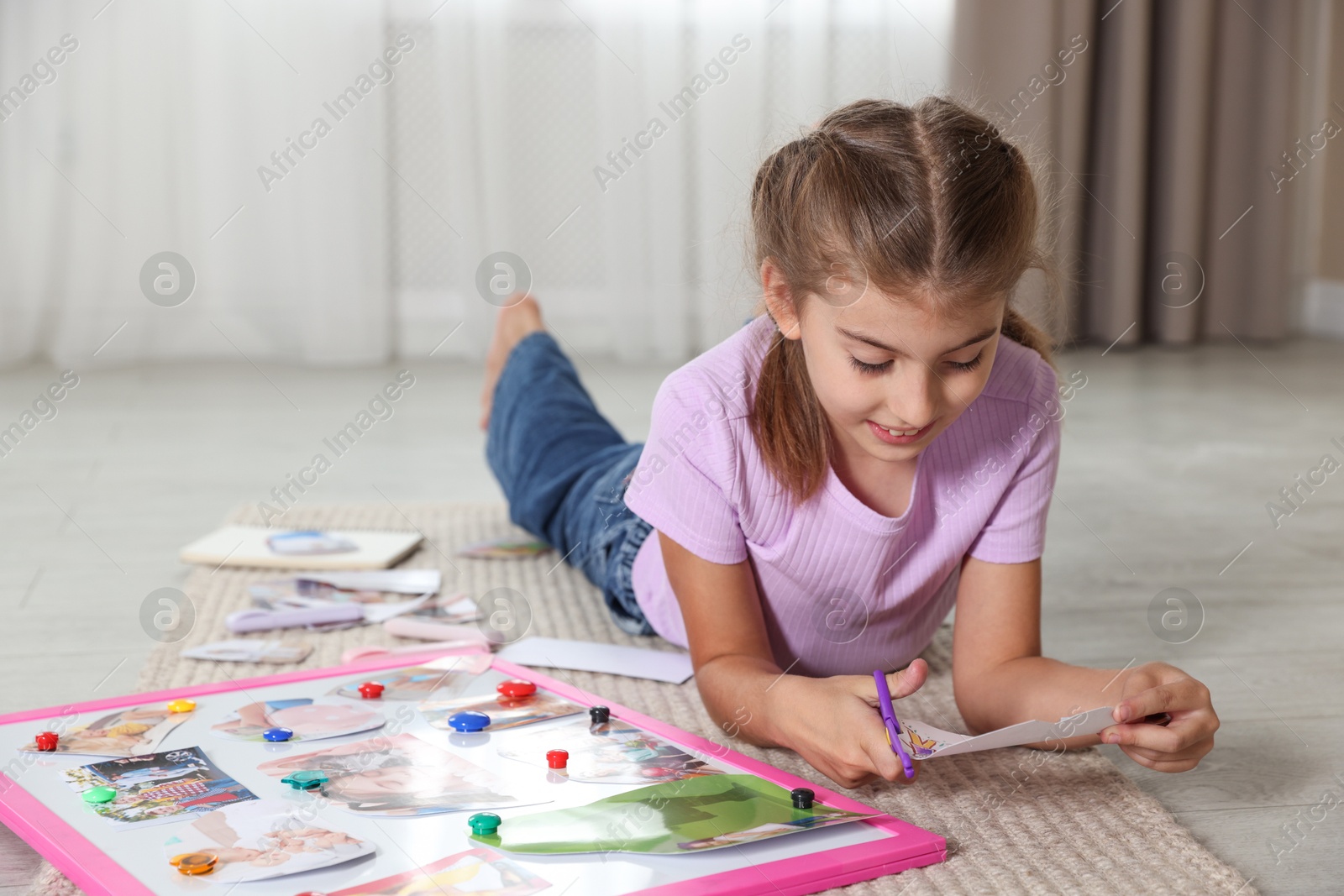 Photo of Creating vision board. Girl cutting out picture on floor indoors