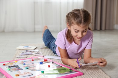 Creating vision board. Girl cutting out picture on floor indoors