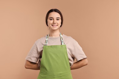 Photo of Girl in apron on pale brown background. Work for teenagers