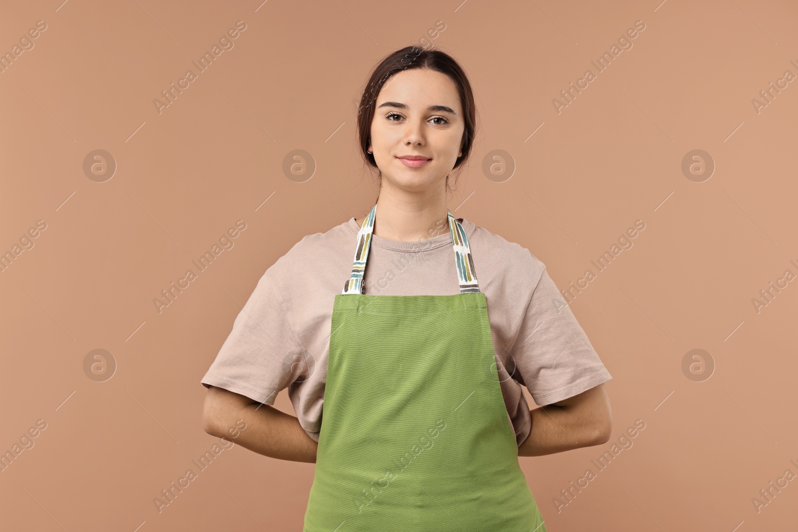 Photo of Girl in apron on pale brown background. Work for teenagers