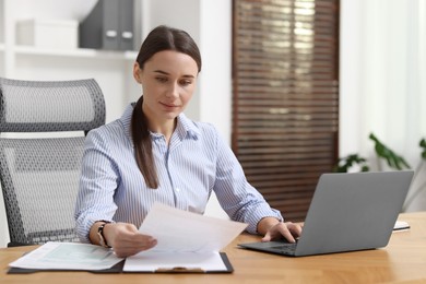 Photo of Businesswoman with document working at table in office