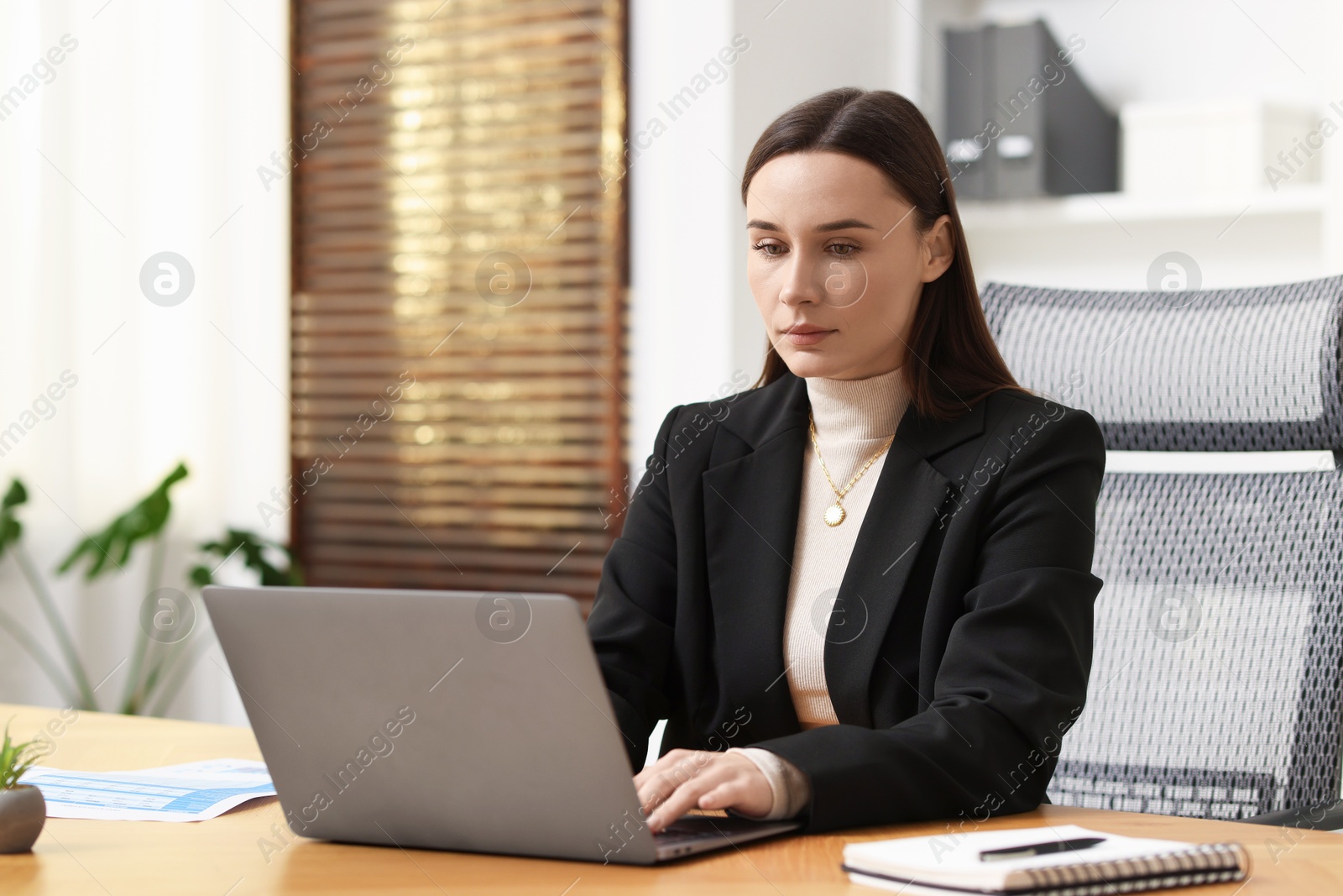 Photo of Businesswoman working with laptop at table in office