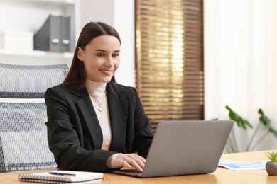 Photo of Businesswoman working with laptop at table in office