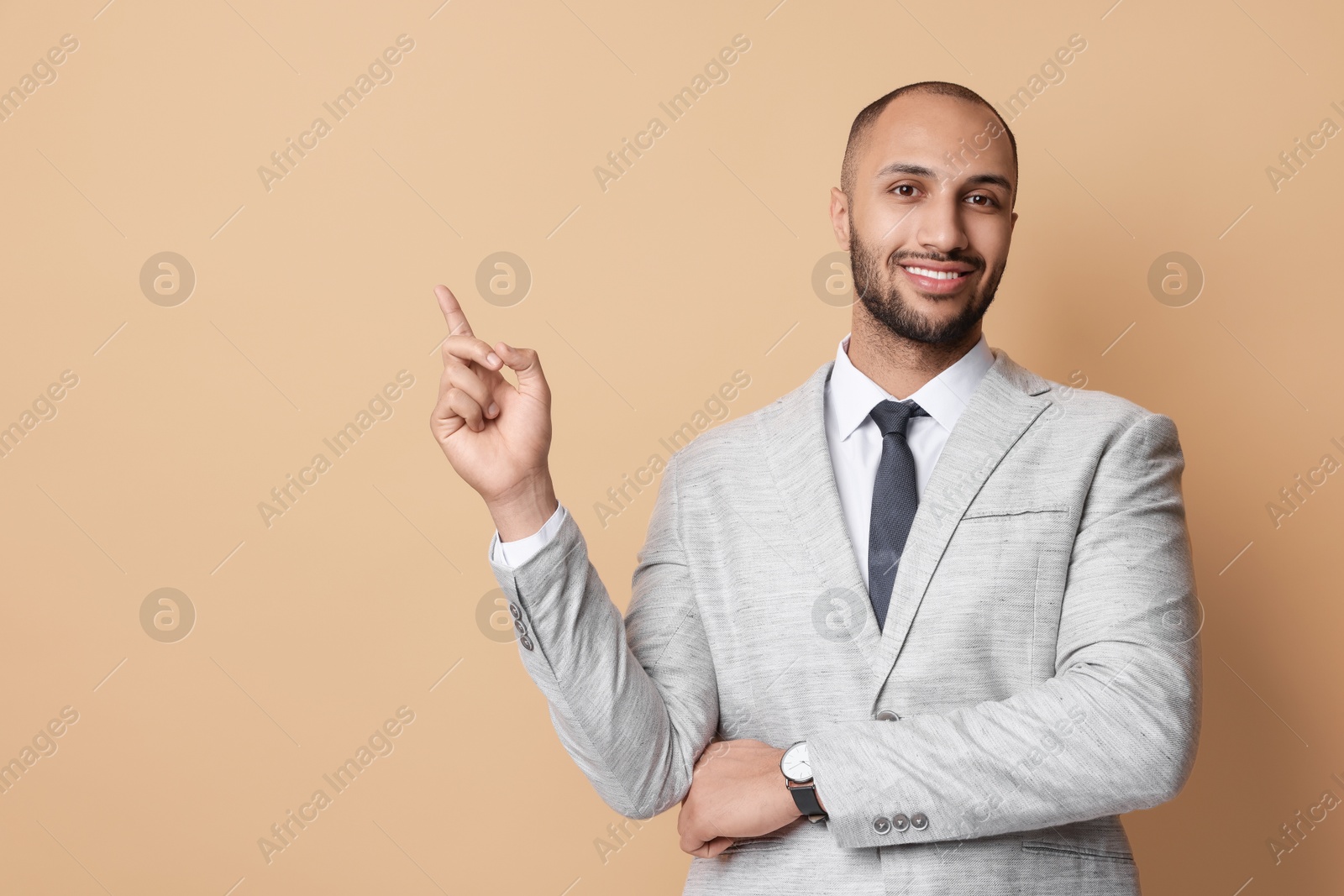 Photo of Portrait of businessman pointing at something on beige background, space for text