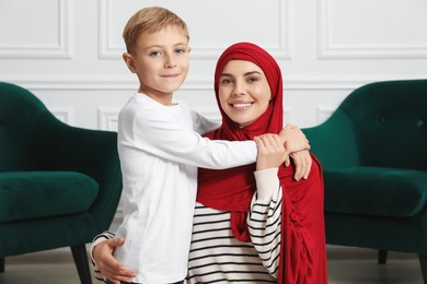 Photo of Muslim woman and her son spending time together at home