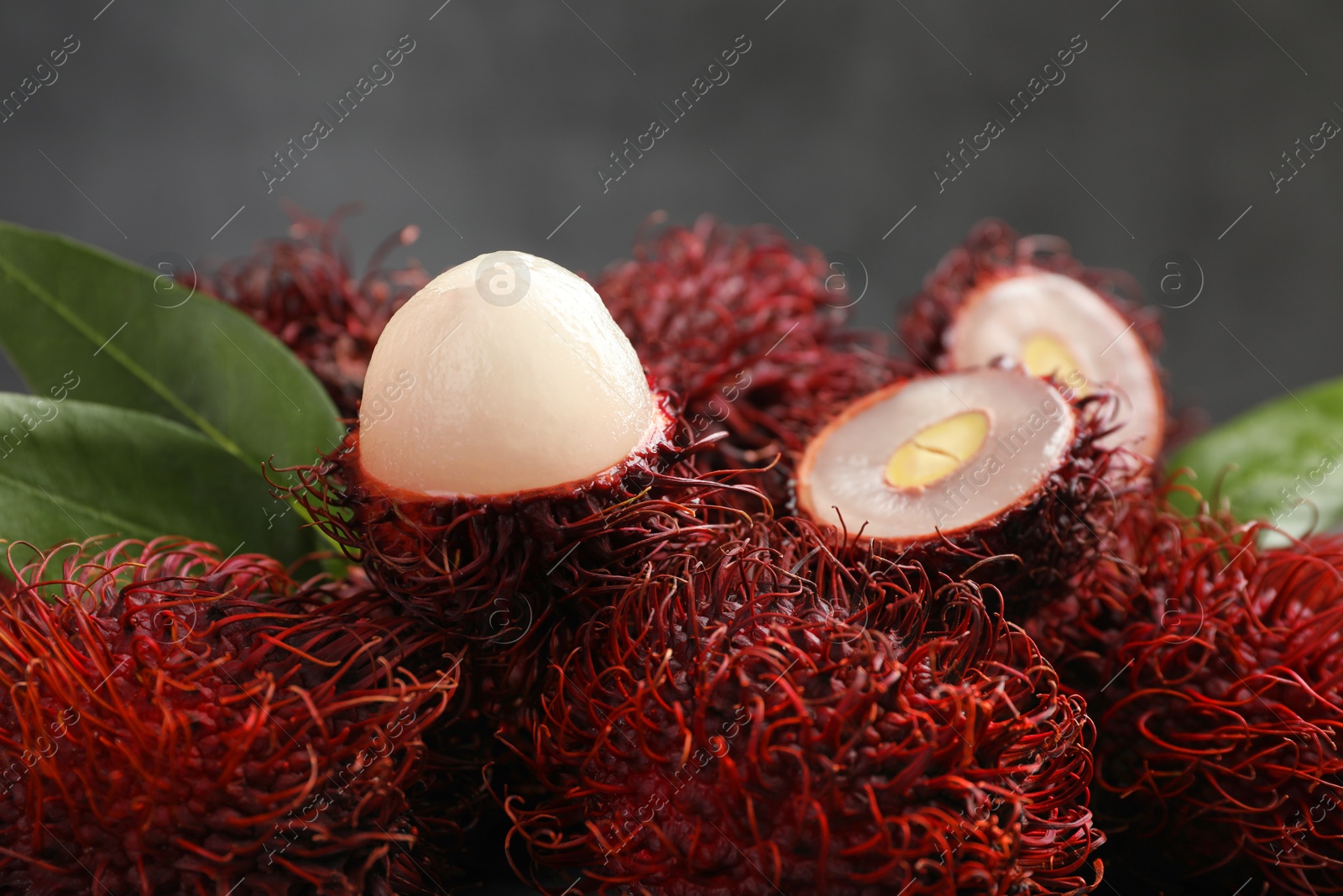 Photo of Delicious ripe rambutans and green leaves on blurred background, closeup