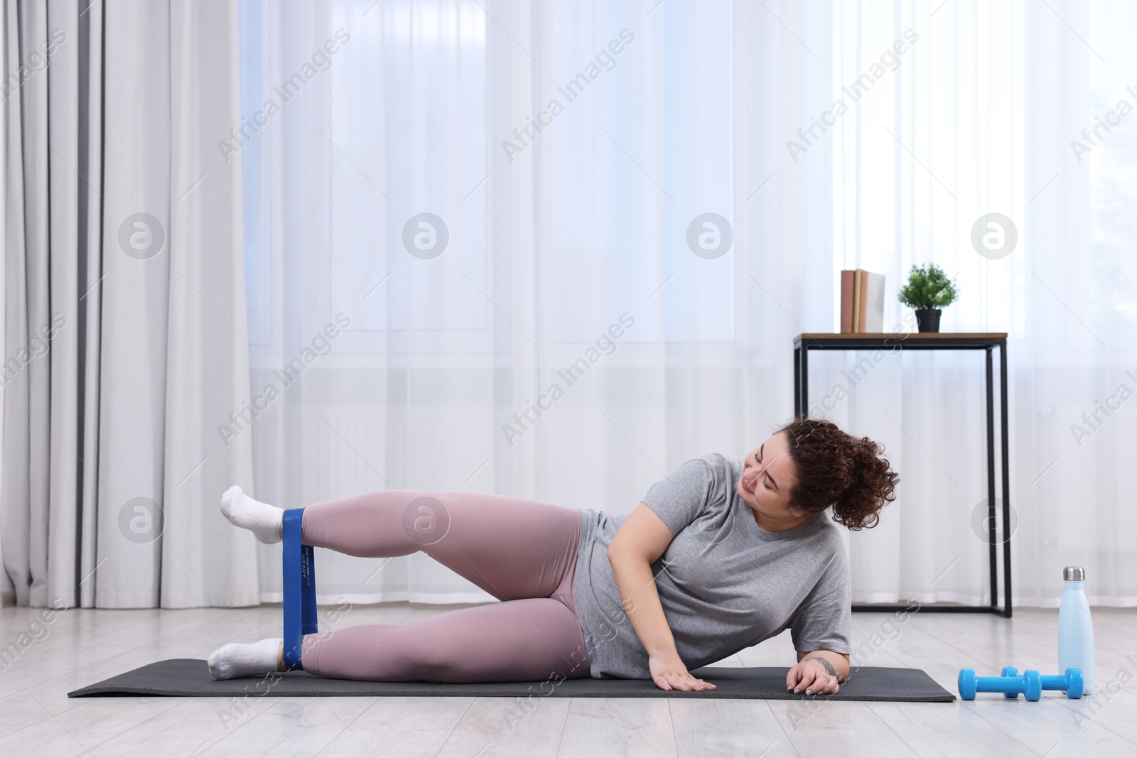 Photo of Woman training with resistance band at home