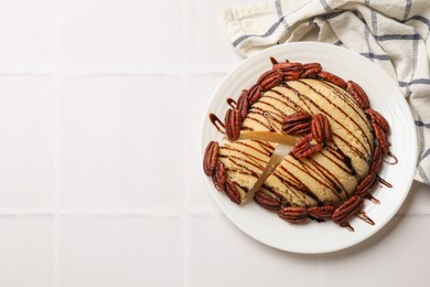 Photo of Delicious sweet semolina halva with pecans on white tiled table, top view. Space for text