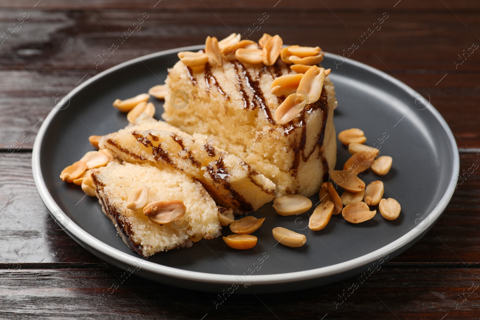 Photo of Delicious sweet semolina halva with peanuts on wooden table, closeup