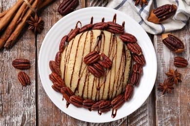 Photo of Delicious sweet semolina halva with pecans and spices on wooden table, flat lay