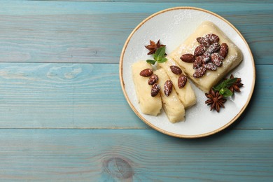 Photo of Delicious sweet semolina halva with almonds, spices and mint on light blue wooden table, top view. Space for text