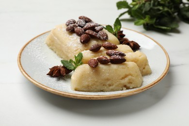 Photo of Delicious sweet semolina halva with almonds, spices and mint on white marble table