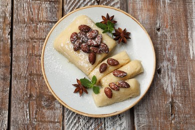 Photo of Delicious sweet semolina halva with almonds, spices and mint on wooden table, top view