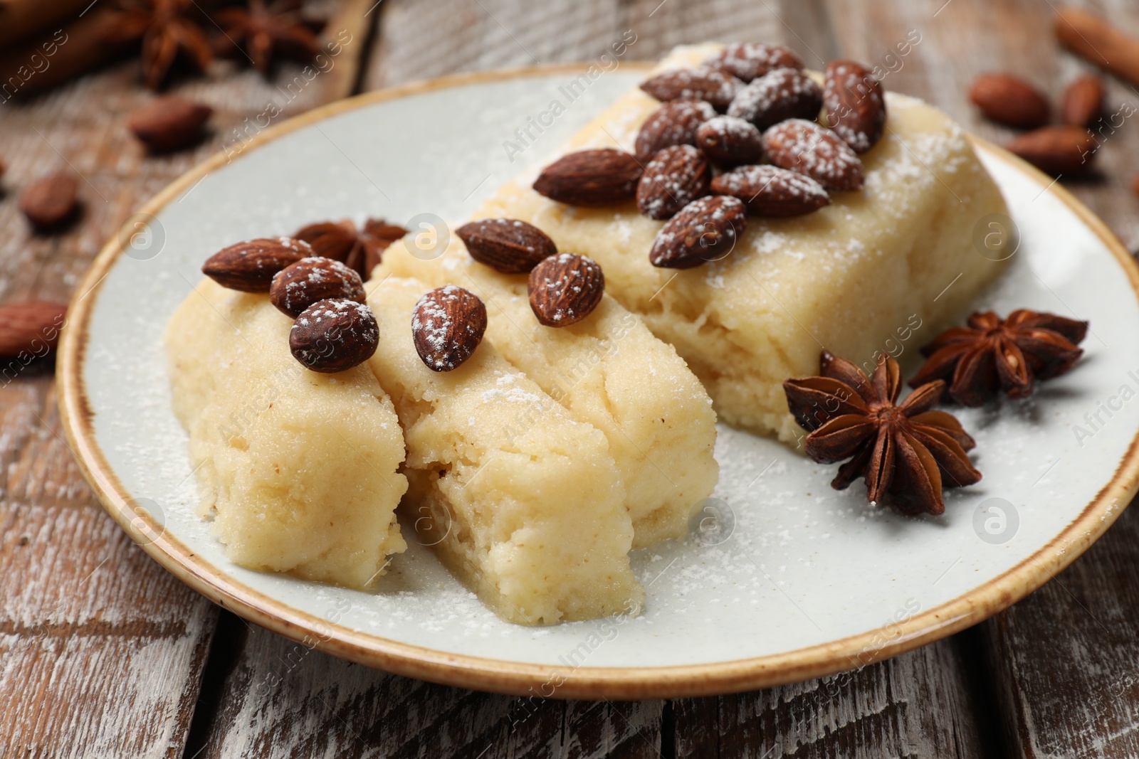 Photo of Delicious sweet semolina halva with almonds and spices on wooden table, closeup