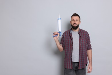 Photo of Man with caulking gun on gray background, space for text