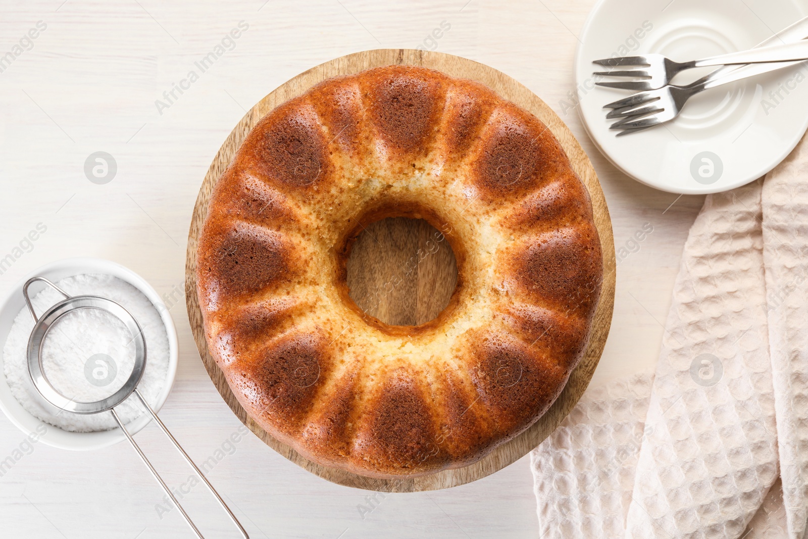 Photo of Freshly baked sponge cake served on white wooden table, top view