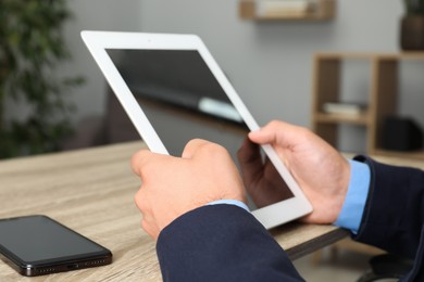 Photo of Businessman with tablet and smartphone at wooden table, closeup. Modern technology