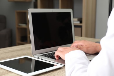 Photo of Businessman using laptop at wooden table, closeup. Modern technology