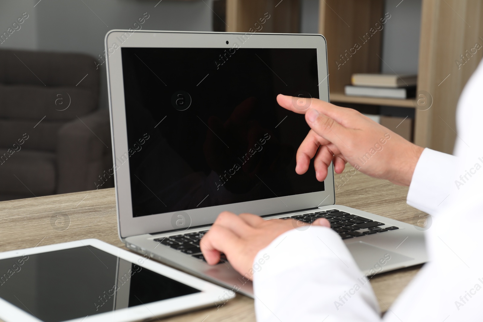 Photo of Businessman using laptop at wooden table, closeup. Modern technology