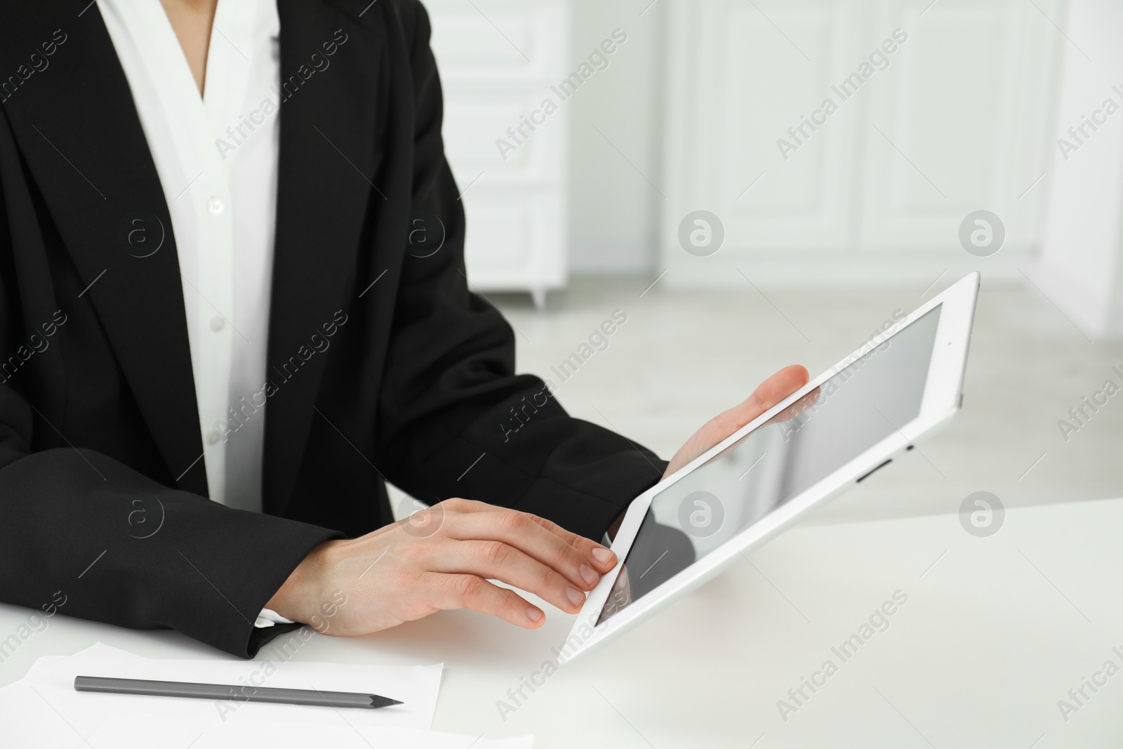 Photo of Businesswoman using tablet at white table indoors, closeup. Modern technology